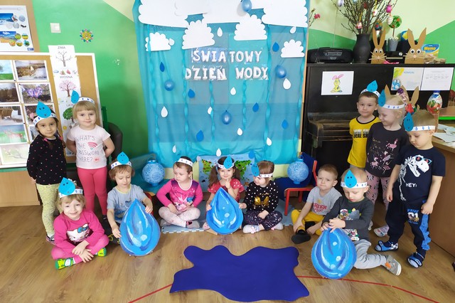 Grupa dzieci przy dekoracji ściennej w kolorze niebieskiej i o tematyce wody