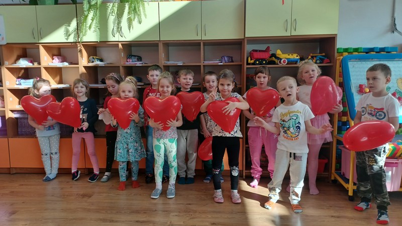 Dzieci z czerwonymi balonami w kształcie serca.