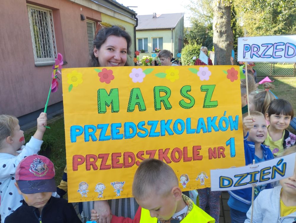 kobieta trzyma transparent z napisem Marsz przedszkolaków z Przedszkola nr 1