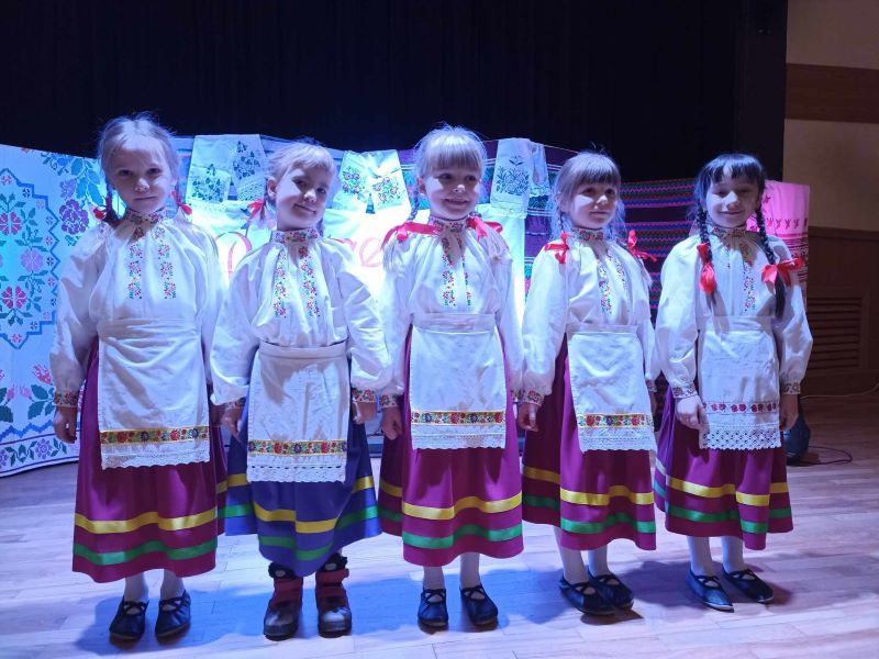 Dzieci stoją na scenie Hajnowskiego Domu Kultury, ubrane są w ludowe stroje.